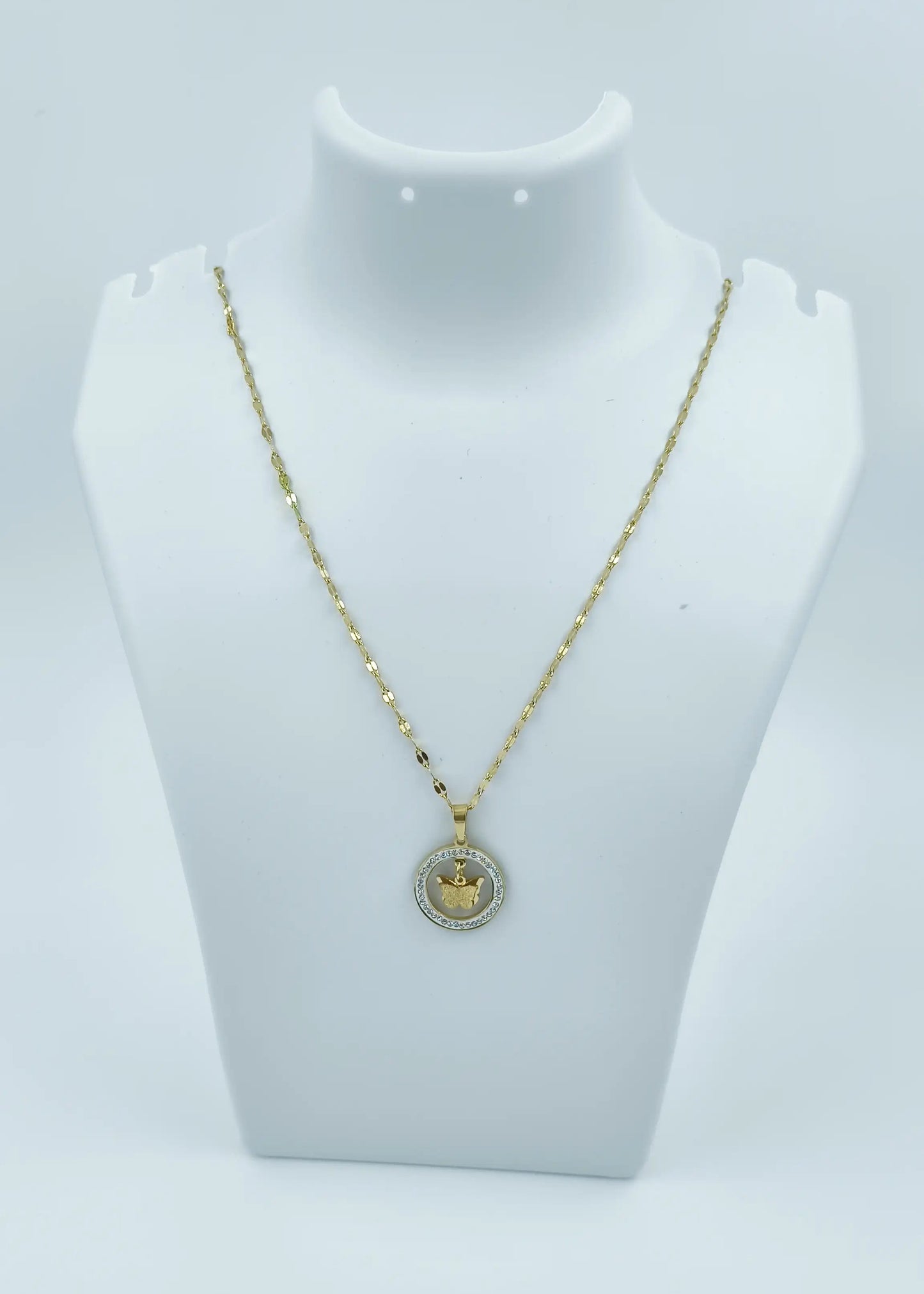 Gold necklace with a pendant on a mannequin bust against a white background
