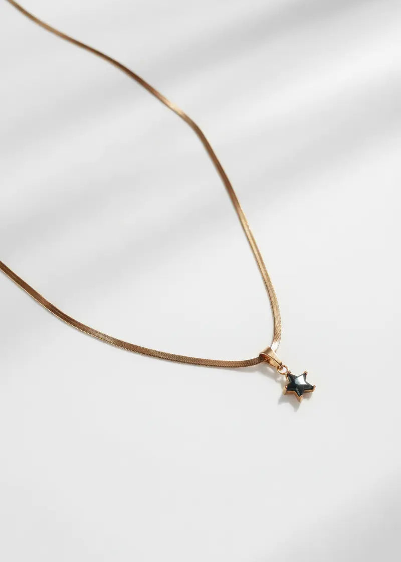 Gold necklace with a star-shaped pendant on a white background