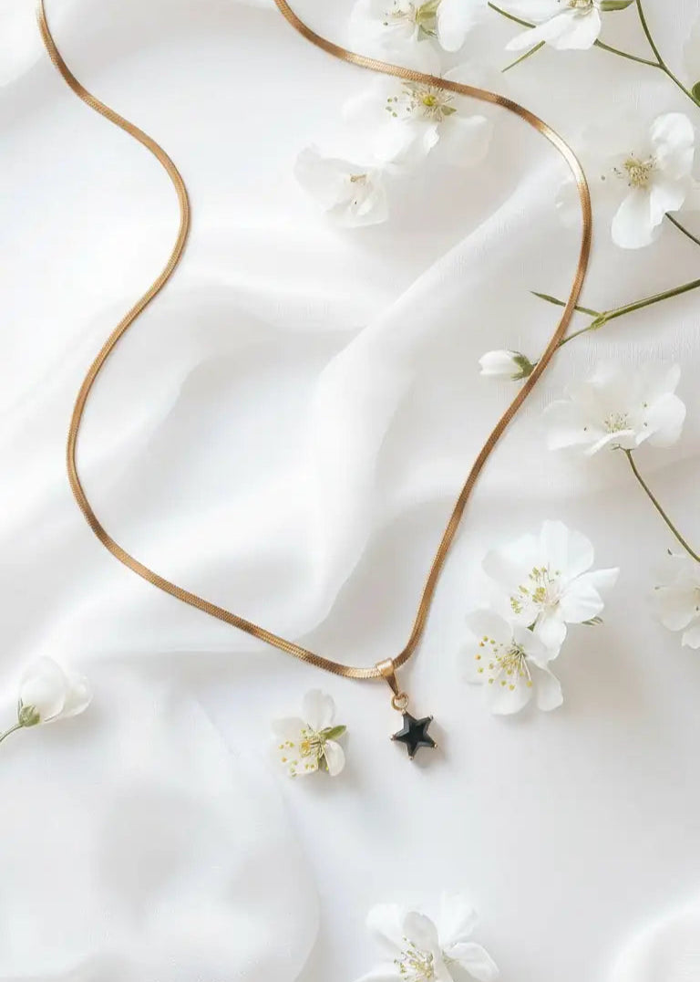 Gold necklace with a star pendant on a white fabric background