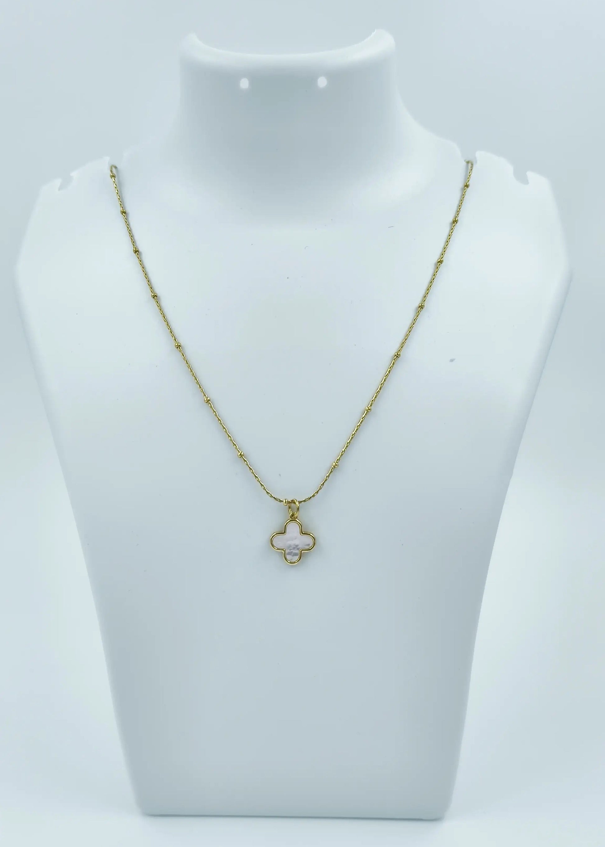 Gold necklace on a white mannequin bust against a white background