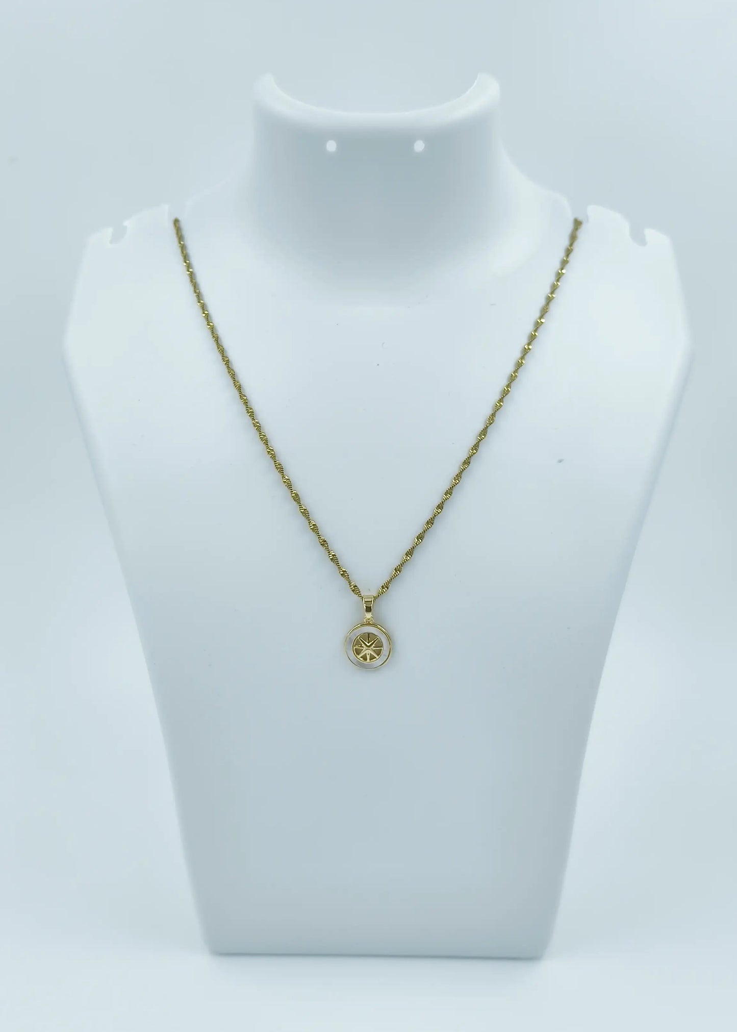 Gold necklace with a pendant on a mannequin bust against a white background