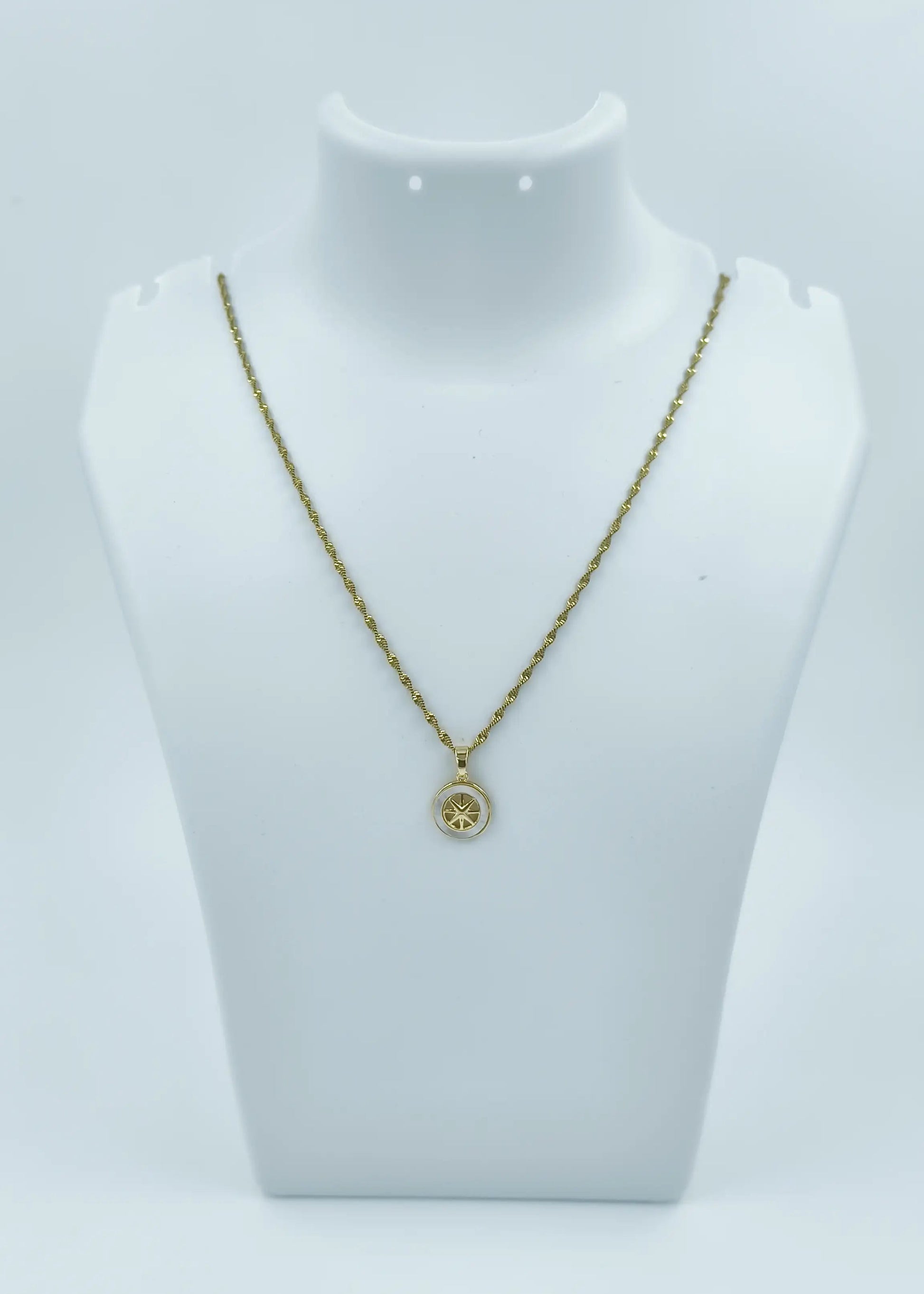 Gold necklace with a pendant on a mannequin bust against a white background