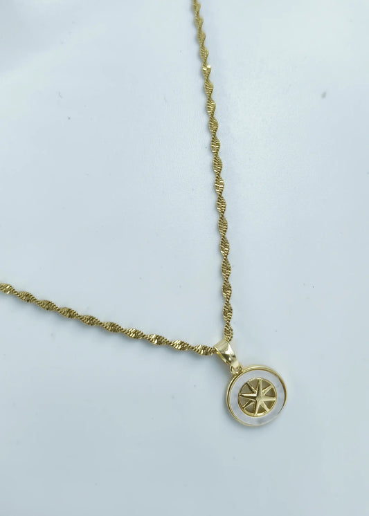 Gold necklace with a circular pendant on a light gray background