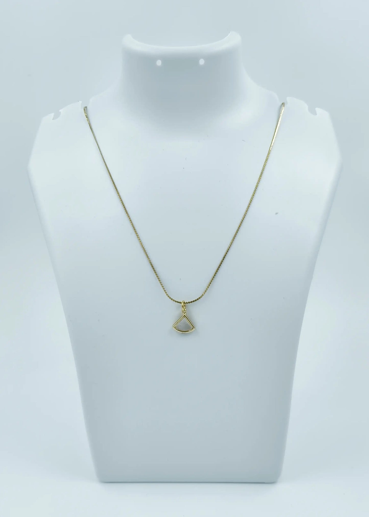 Gold necklace with a pendant on a mannequin bust against a white background