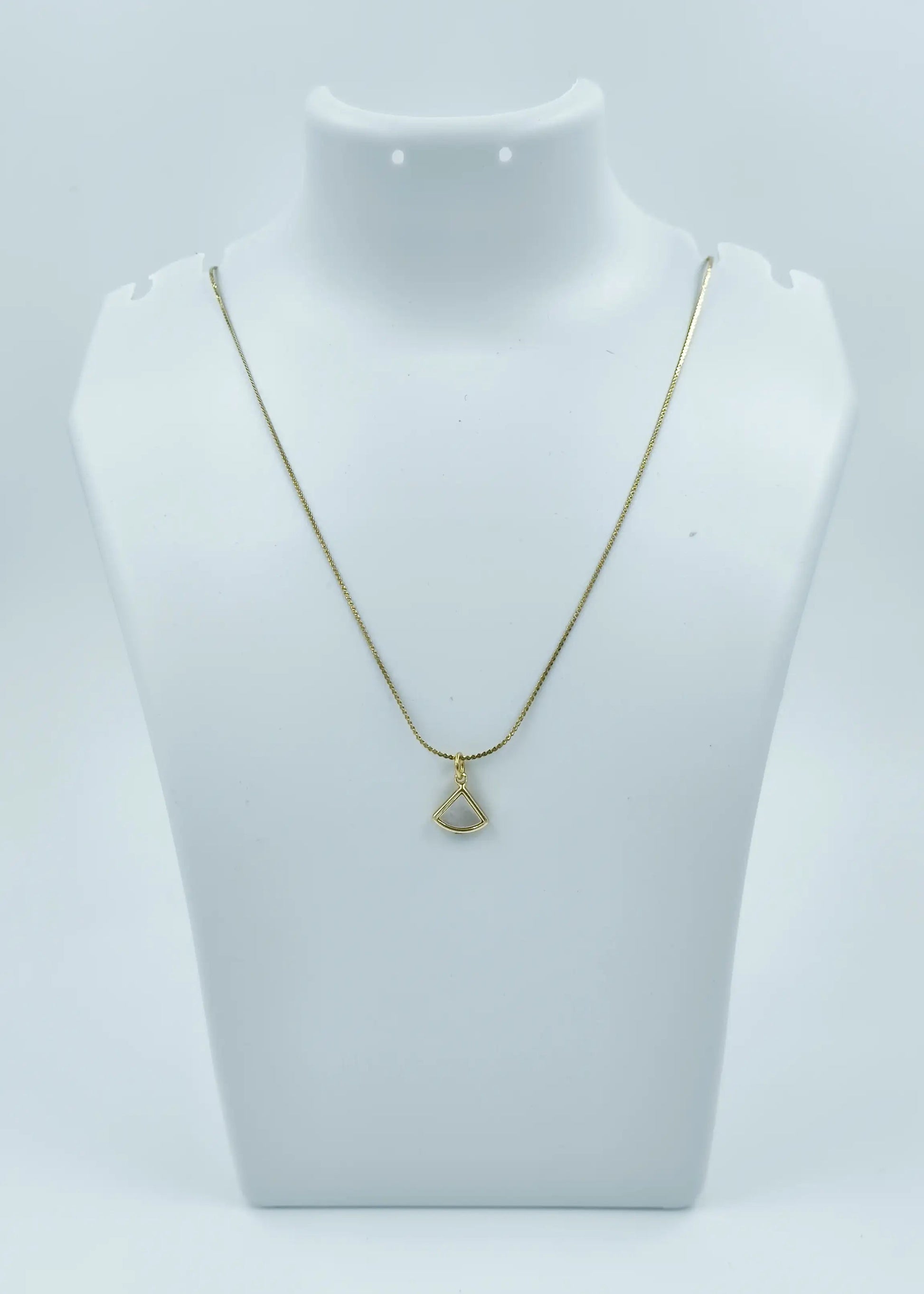 Gold necklace with a pendant on a mannequin bust against a white background