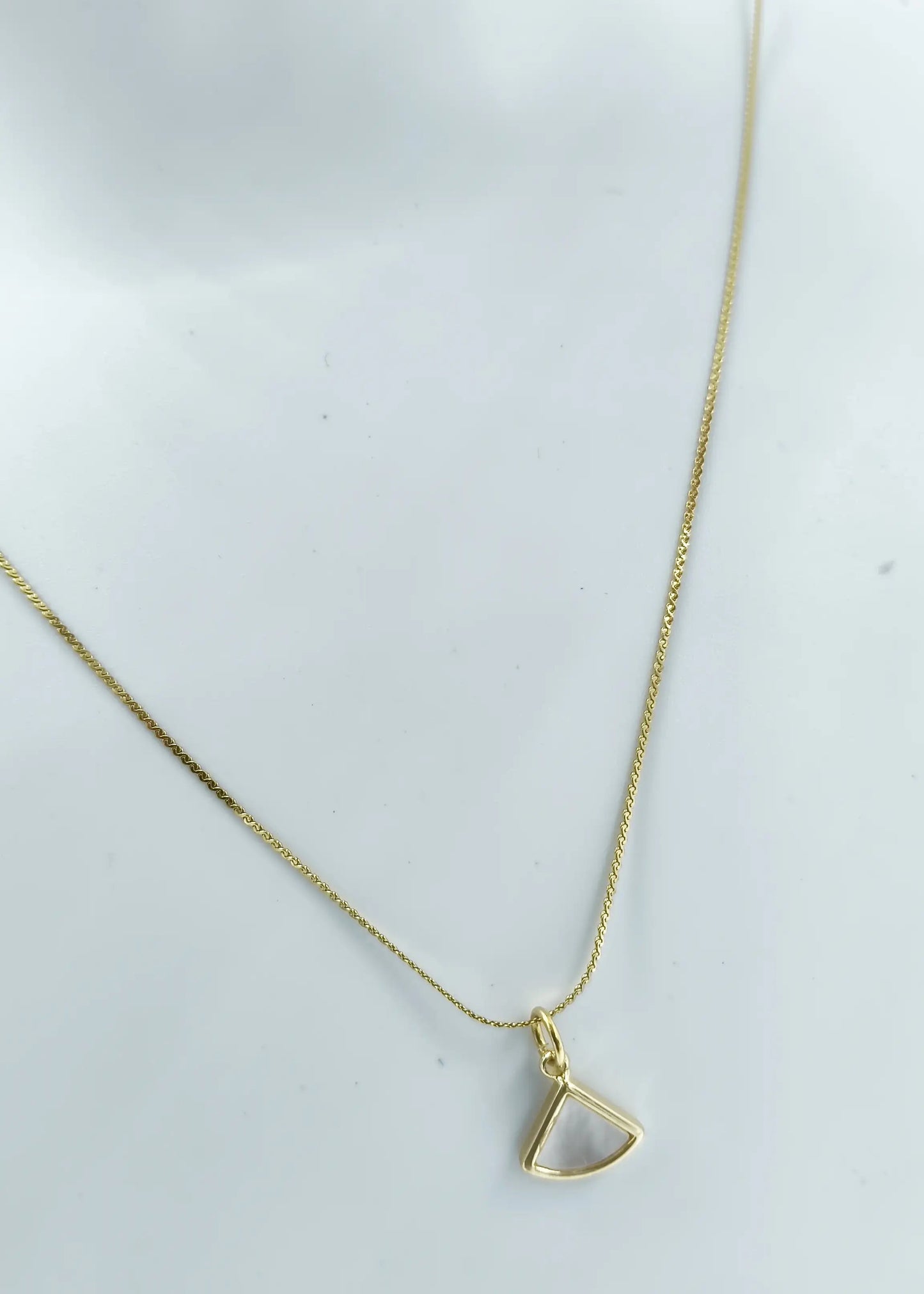 Gold necklace with a triangular pendant on a white background