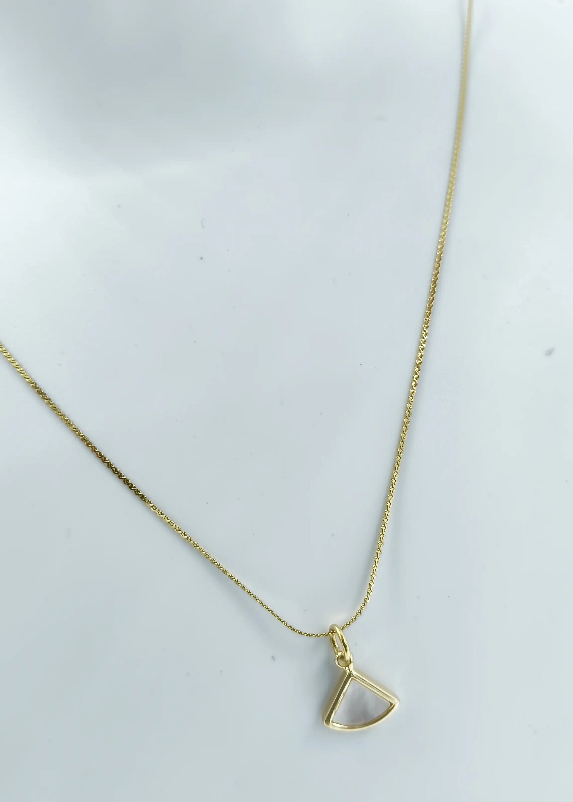 Gold necklace with a triangular pendant on a white background