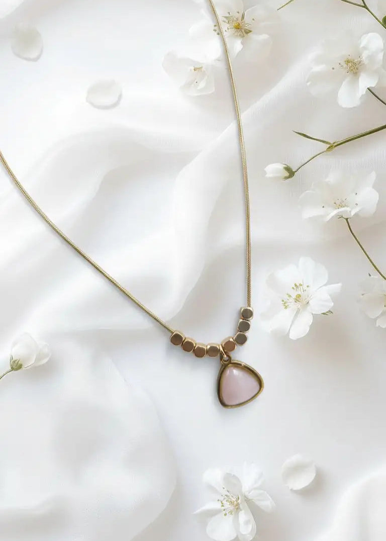 Necklace with a teardrop pendant on a white fabric background with small white flowers