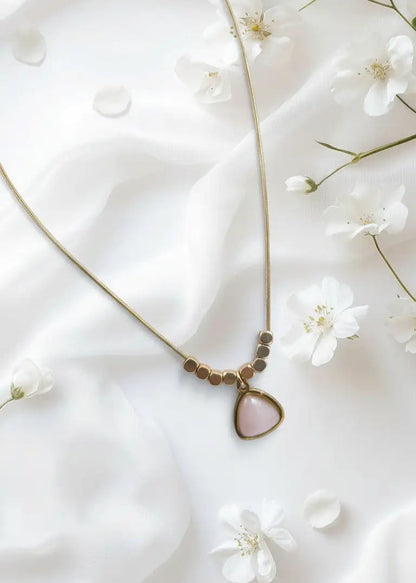 Necklace with a teardrop pendant on a white fabric background with small white flowers