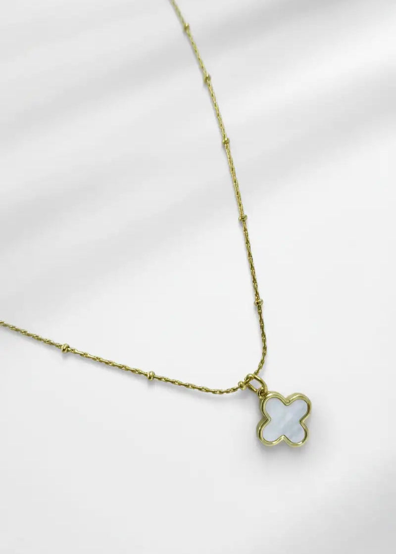 Gold necklace with a clover-shaped pendant on a white background