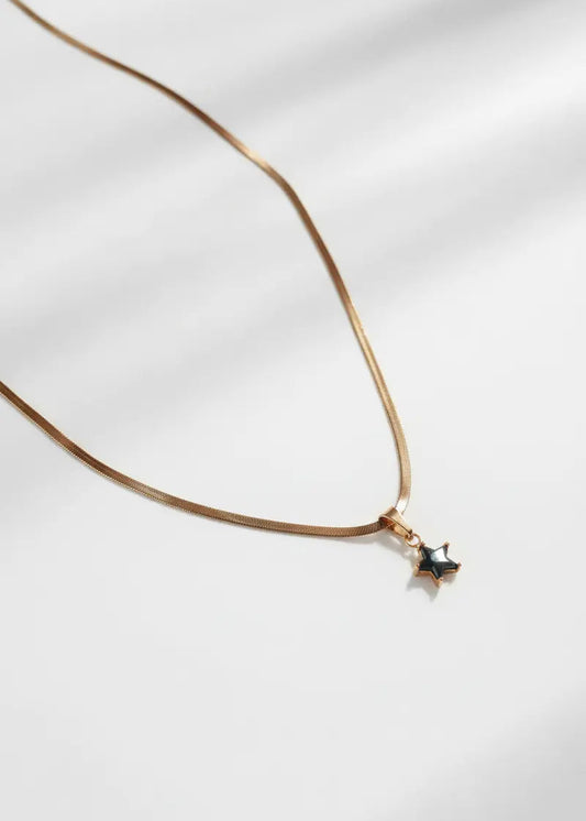 Gold necklace with a star-shaped pendant on a white background