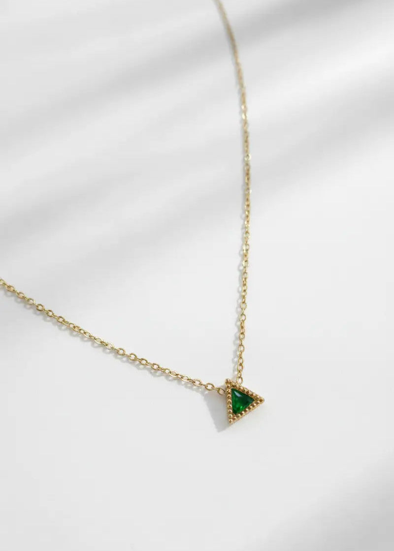 Gold necklace with a green triangle pendant on a white background