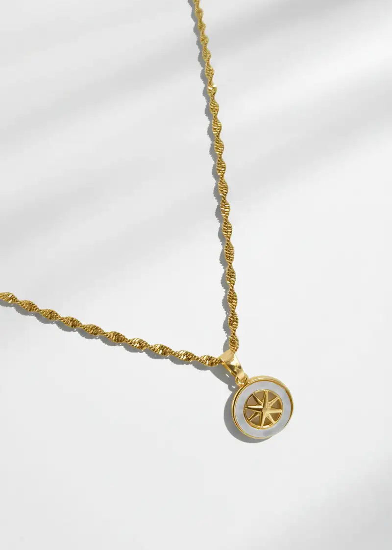 Gold necklace with a circular pendant on a white background