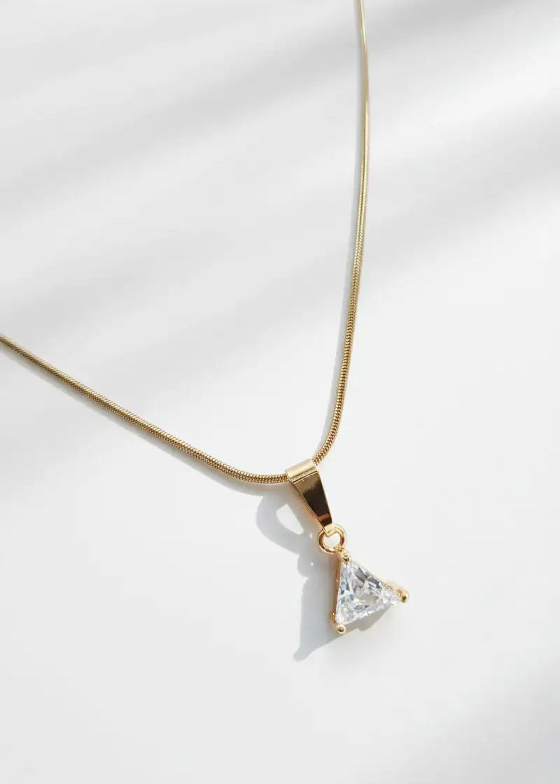 Gold necklace with a triangular pendant on a white background